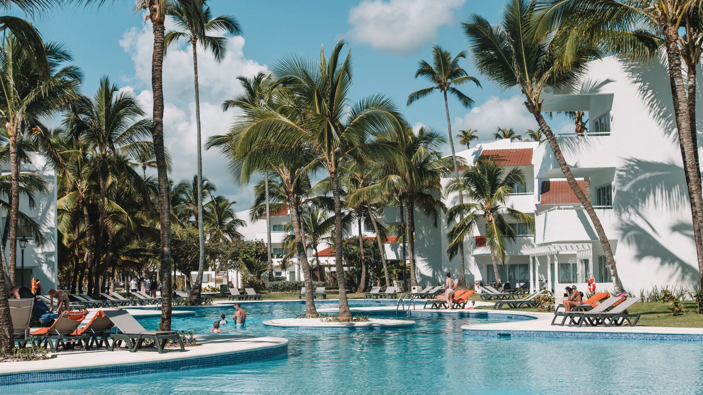 Resort pool surrounded by palm trees and villas in Punta Cana, Dominican Republic